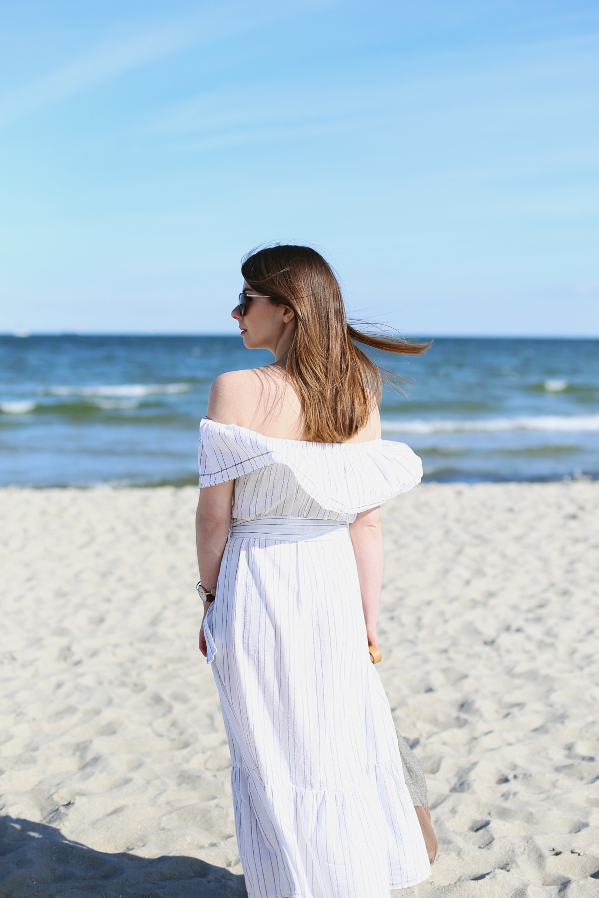 Biała sukienka z odkrytymi ramionami - sesja modowa na plaży